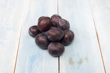 Plums on blue wooden board, top view