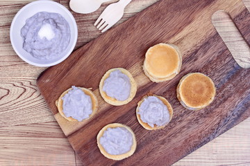 Mini pancake topped stirred taro on wood. 