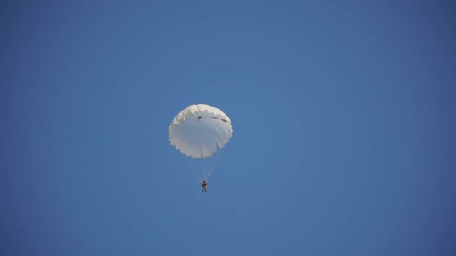 paratrooper landed on the grass and meet his friends, blue sky, white parachute