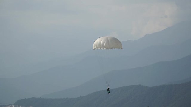 paratrooper landed on the grass, blue sky, white parachute