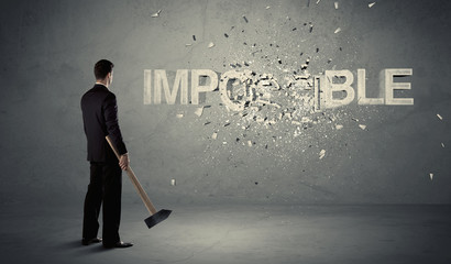 Business man hitting impossible sign with hammer