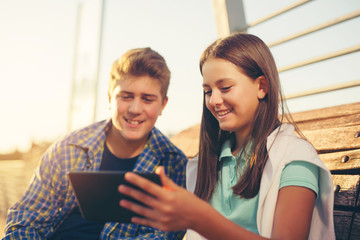 Teenagers Girl And Boy On Bench Using Digital Tablet, selective focus