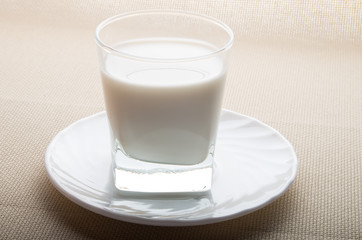 One glass of milk on a white saucer in backlit