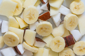 Pieces of Apple, Coconut and Banana on a white plate