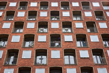 Red and yellow brick facade with deep retracted balcony holes of an apartment building in Copenhagen Denamrk
