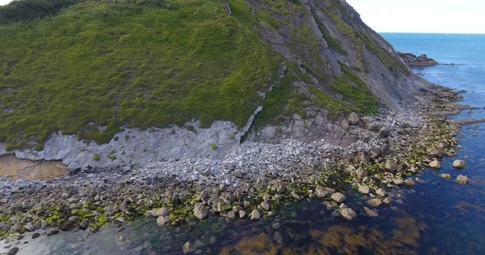 Aerial view across the sea past steep cliffs and rocky coastline at dawn