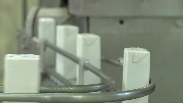 Automated machine processes milk, milkshake and juice boxes in a factory CLOSE UP, DETAILS