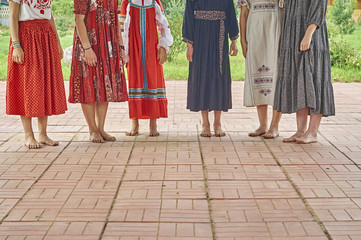 Fototapeta na wymiar Girls in folk dresses standing barefoot on the concert of folk music outdoors 