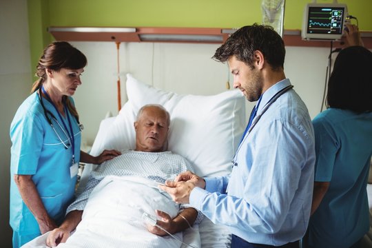 Male doctor showing report to senior patient on digital tablet