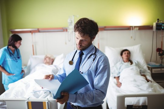 Doctor checking reports of patient in hospital