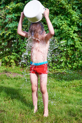 Little boy pouring water over in summer