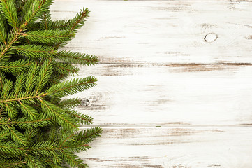 Green Christmas spruce branch on wooden background