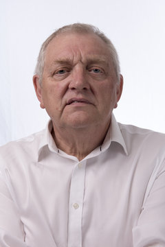 Close up portrait image of a mature man looking annoyed. Taken on a white background. 