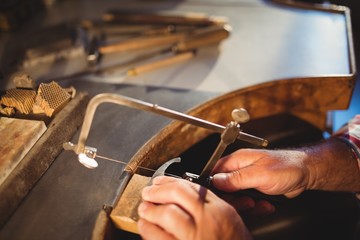Goldsmith shaping metal with coping saw