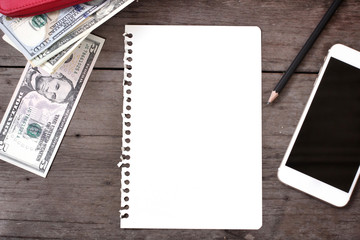 Dollars and blank notepad with smart phone