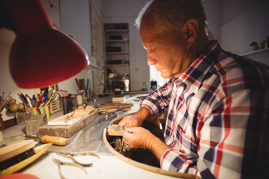Goldsmith shaping metal with pilers
