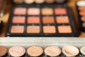 Blurry professional visagiste workspace. Blusher and cream concealer pallet.