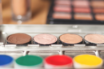 Blurry professional cosmetic background. Cream concealer pallet and aqua make up. Working with skin defects. Pastel and contrast colors.