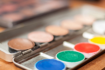 Blurry professional cosmetic background. Cream concealer pallet and aqua make up. Working with skin defects. Pastel and contrast colors.