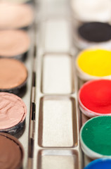 Naklejka premium Blurry professional cosmetic background. Cream concealer pallet and aqua make up. Working with skin defects. Pastel and contrast colors.