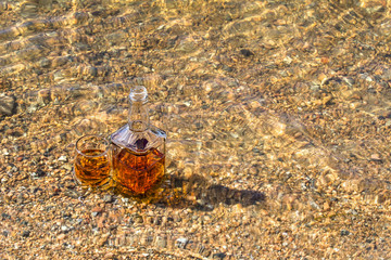 Bottle and glass whiskey are cooled in river