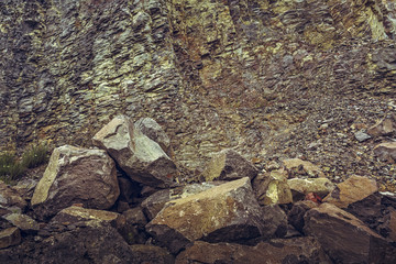 Vertical strata rock wall and big boulders in an deserted basalt quarry near the extinct volcano in Racos, Brasov county, Romania.