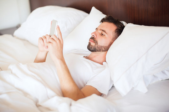 Man using a smartphone on his bed