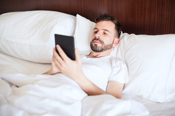 Man reading an e-book in bed