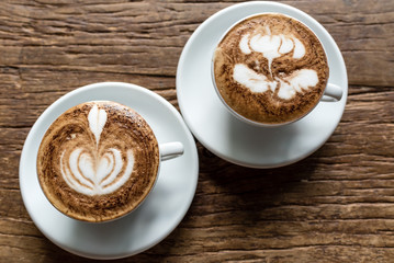 Two Hot cappuccino in white cup and plate on Wooden Background table