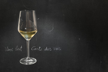 Glass of white wine on dark chalkboard