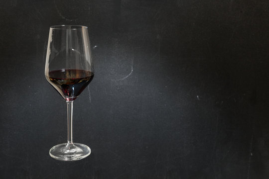 Glass of red wine on dark chalkboard