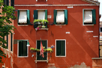Picturesque red building with flag of Venice. In Venice, Italy.