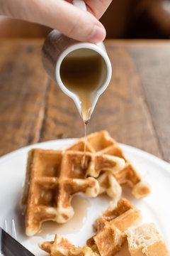 Pouring Maple Syrup Onto Plate Of Waffle