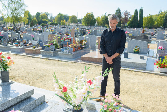 Man stood looking at gravestone