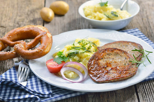 Eine bayerische Spezialität: Gebratene Milzwurst mit Kartoffelsalat und Breze - Bavarian food: Fried sausage with pieces of spleen served with potato salad
