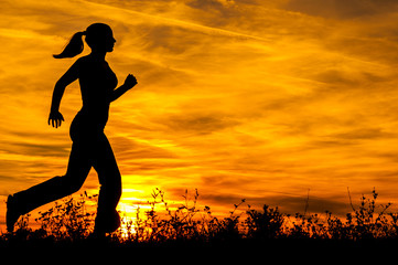 Silhouette of girl running in nature at summer sunset