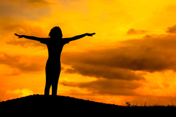 Happy young woman silhouette with twilight sunset.
