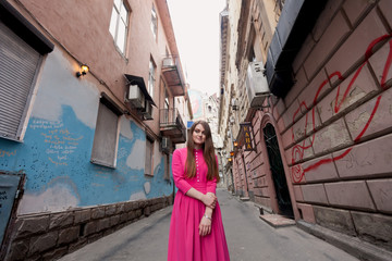 amazing young brunette in pink dress among buildings