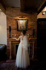 Bride shows her veil and dress near the fireplace