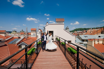 Happy wedding couple are dancing among red roofs