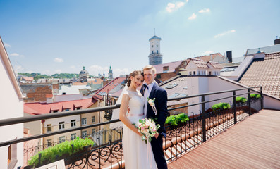 Happy wedding couple hud among city roofs