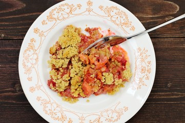Plum crumble in white plate on dark wooden background