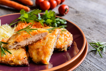 Baked pork cutlets coated in cheese and carrot with salad