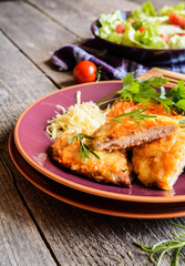 Baked pork cutlets coated in cheese and carrot with salad