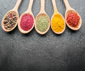 Assortment of colorful spices in the wooden spoons.