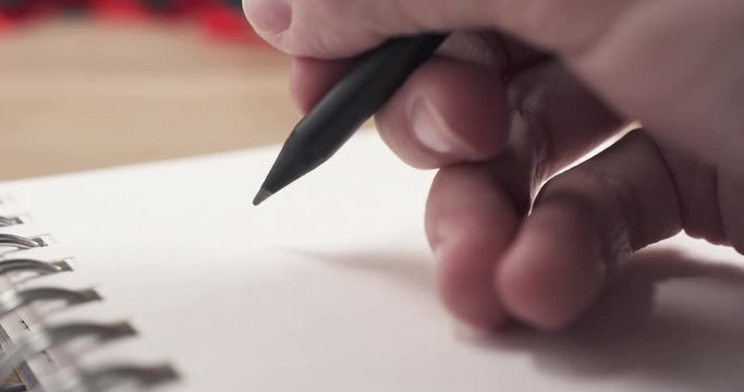 young man hand writes gift list on notepad