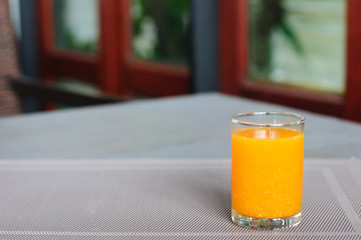 Small single glass of orange juice on napery