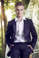 Young man in a suit sitting on a chair in the garden