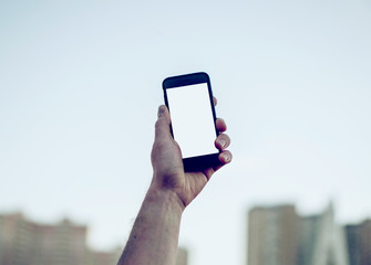Man's hand shows mobile smartphone in vertical position, blurred