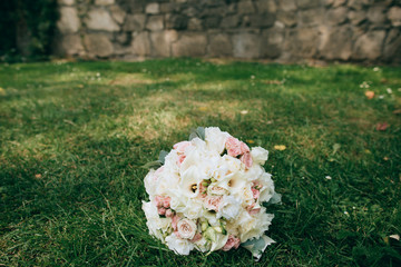 Wedding bridal bouquet of delicate pink and white flowers lying on green grass. wedding concept